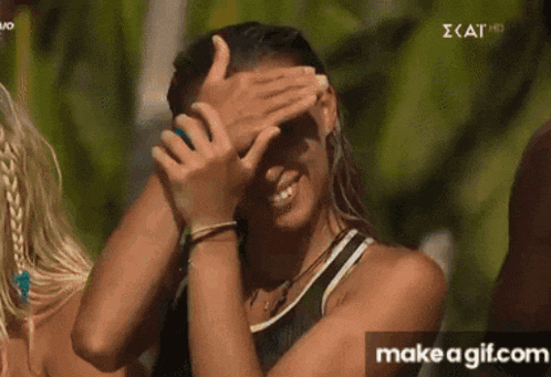 a woman is covering her eyes with her hands while smiling .