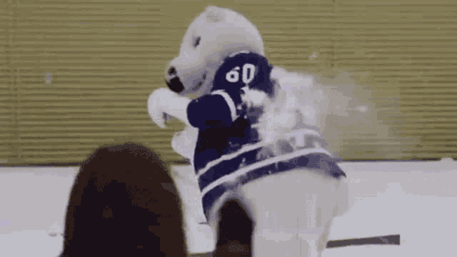 a polar bear mascot is standing on a ice rink .