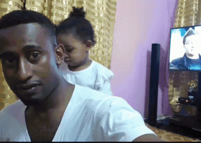 a man holds a little girl on his shoulders in front of a tv