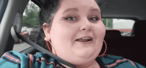 a woman wearing hoop earrings is sitting in a car