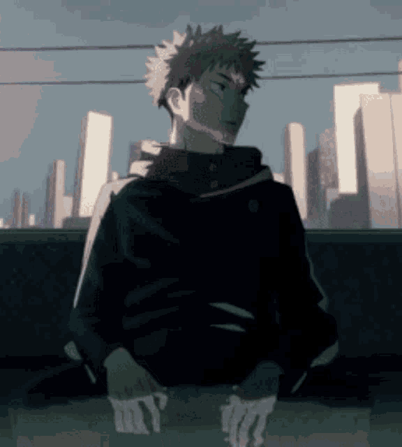 a man in a black jacket is sitting on a bench in front of a city skyline .