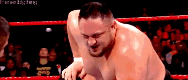 a man is wrestling another man in a ring without a shirt on .