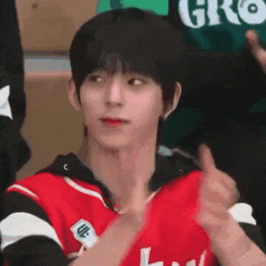 a young man in a red and black jersey is giving a thumbs up sign .