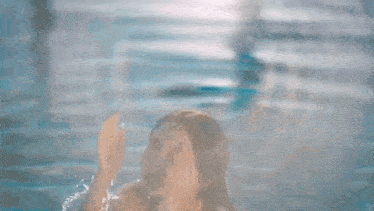 a woman in a bikini is standing in a pool .
