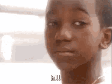 a close up of a young boy making a funny face and saying eu .