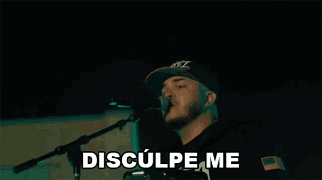 a man singing into a microphone with the words disculpa me below him