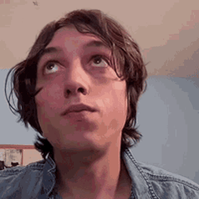 a man in a denim shirt is looking up at the camera