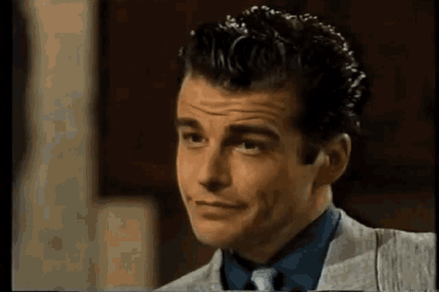 a man in a suit and tie is smiling and making a funny face .
