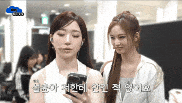 two girls are standing next to each other and one is holding a cell phone with the words day mixx on the bottom