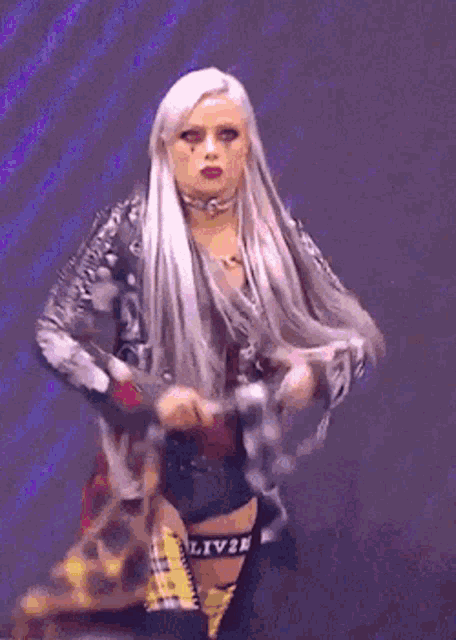 a woman with long white hair and a choker is standing in front of a purple and blue background .