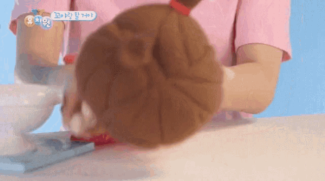 a person in a pink shirt is holding a stuffed animal in their hand