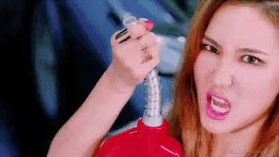 a woman is holding a gas pump in her hand and making an angry face .