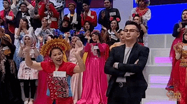 a man in a suit and glasses is standing in front of a crowd of people .