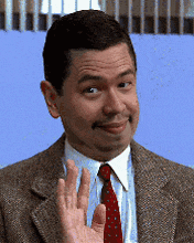 a man in a suit and tie waving his hand