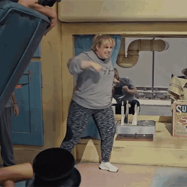 a woman is dancing in front of a box that says su