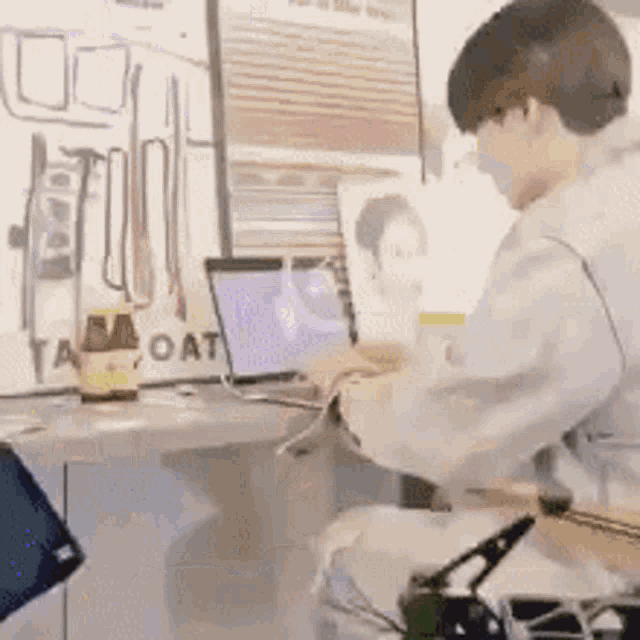 a man is sitting at a desk with a laptop and a picture on it .