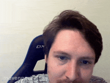 a man with a beard sits in a dx chair