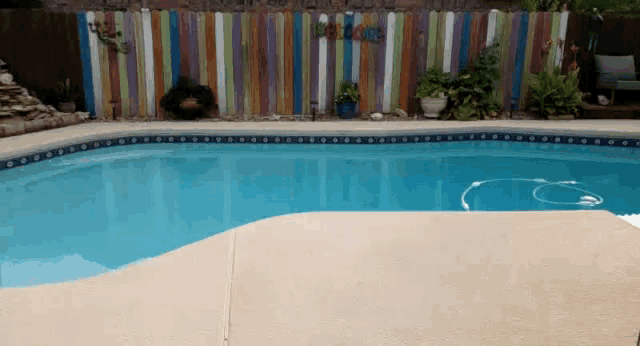 a swimming pool with a colorful fence behind it and a sign that says welcome