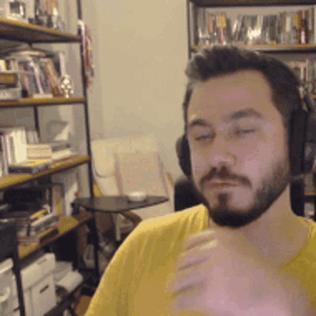 a man with a beard wearing headphones looks at the camera with his eyes closed