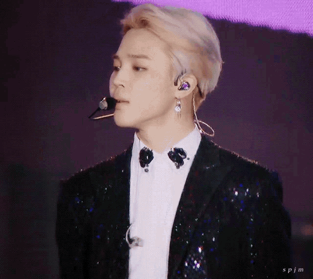a close up of a man wearing a suit and earphones