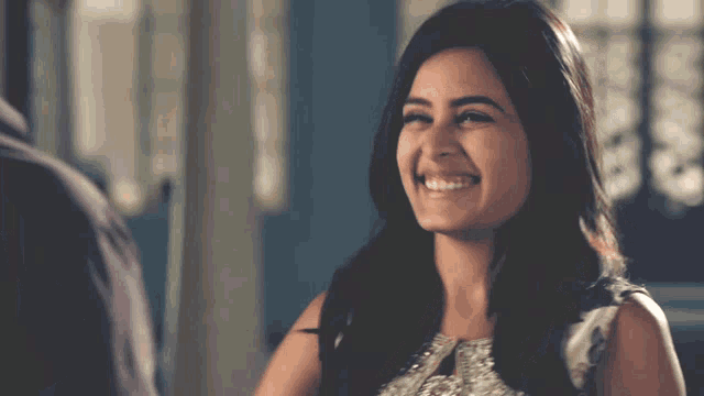 a woman in a white dress is smiling and looking at the camera