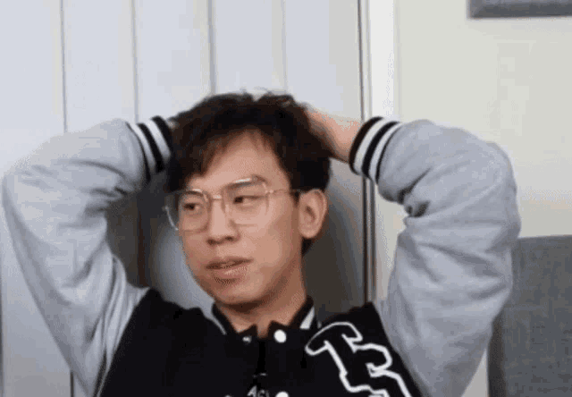 a man wearing glasses and a varsity jacket with the letter b on the back