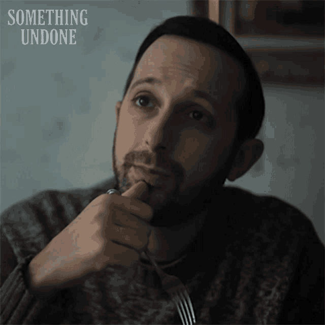 a man with a beard is holding a fork in his mouth with something undone written on the bottom
