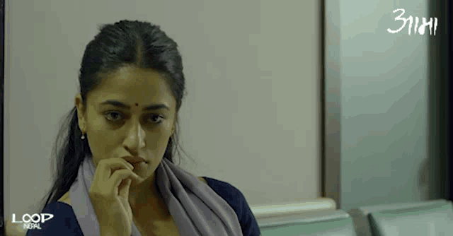 a woman sitting in a waiting room with loop nepal written on the bottom of the screen