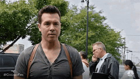 a man wearing a black shirt and brown suspenders is standing on a street .