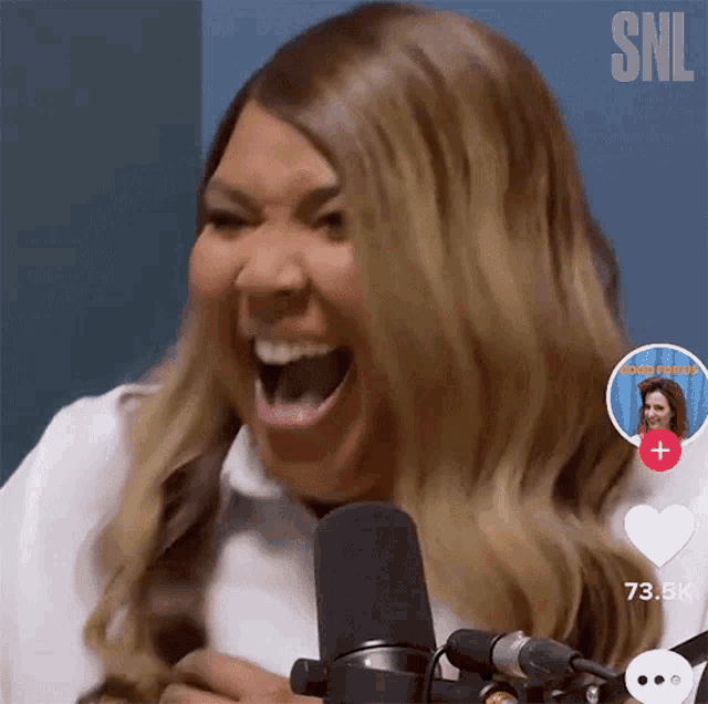 a woman is laughing in front of a microphone with a snl logo in the corner