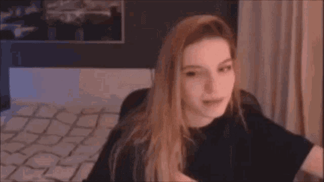 a woman is making a funny face while sitting in front of a bed .