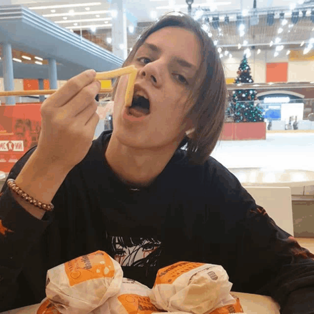 a young man is eating french fries in front of a mcdonald 's advertisement