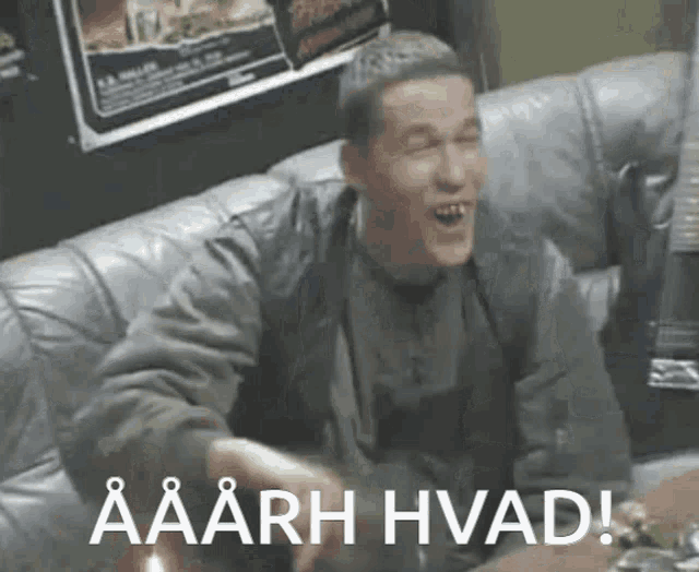 a man is sitting on a couch with the words aaarh hvad on the bottom