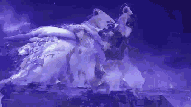 a woman in a white dress is laying on a stage in a purple light .