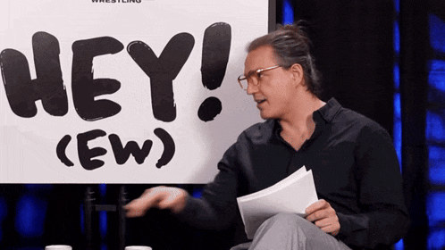 a man sitting in front of a sign that says hey ew