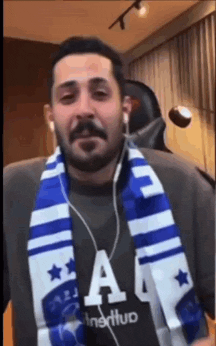 a man with a beard and scarf around his neck is wearing headphones .