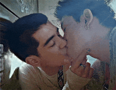 two young men are kissing each other while smoking cigarettes .