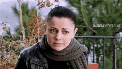 a woman wearing a scarf and a leather jacket looks sad
