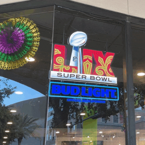 a super bowl bud light sign hangs from a store window