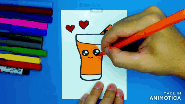 a person is drawing a cup of orange juice with hearts on it
