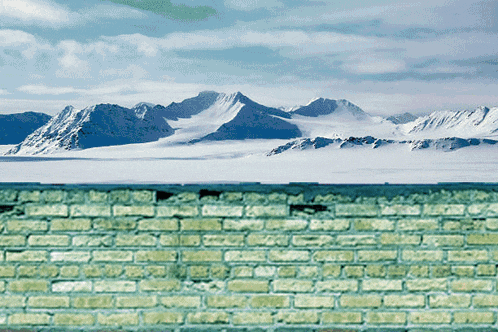 a green brick wall with a mountain in the background