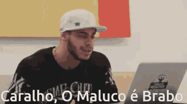 a man sitting in front of a laptop with the words caralho o maluco e brabo