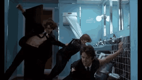 a group of men are dancing in a bathroom in front of a sink
