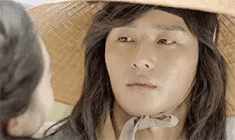 a man with long hair is wearing a straw hat .