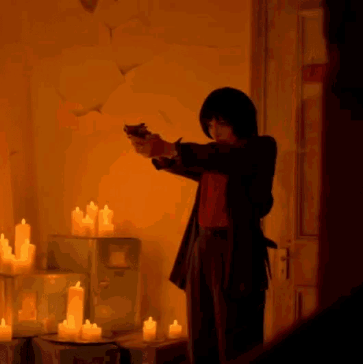 a person holding a gun in front of candles in a room