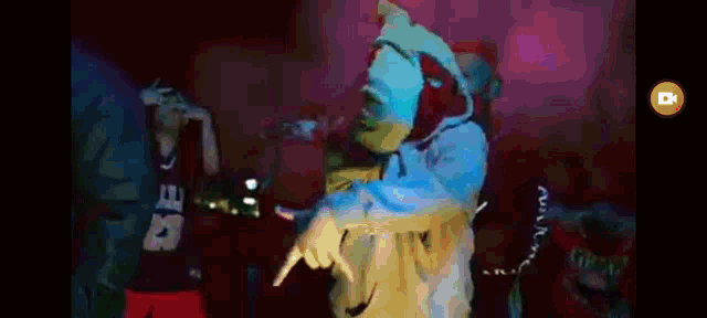 a man in a blue hoodie is dancing in front of a crowd in a club .