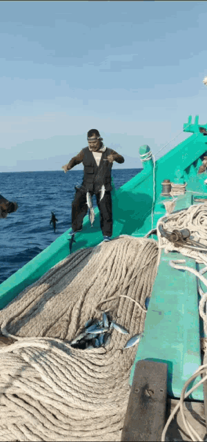 a man is standing on a boat holding a fish in his hand