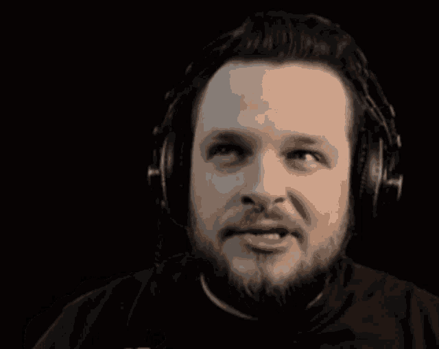 a man with a beard wearing headphones is making a funny face