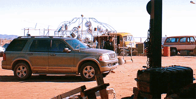 a silver suv is parked in a dirt field