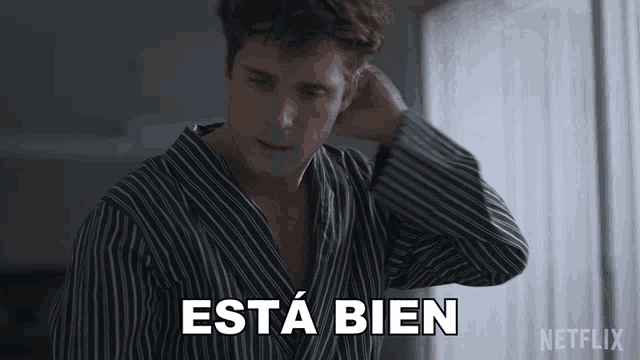 a man in a striped shirt says esta bien in white letters